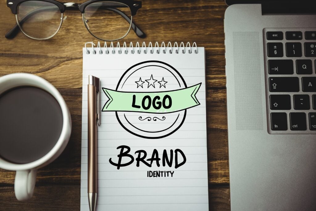 a picture of a brand identity drawing on paper with a mug and laptop on a table