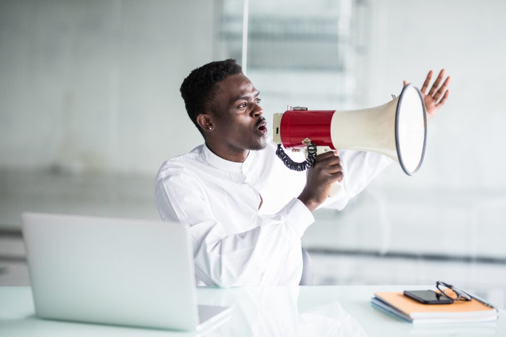 a business man holding a megaphone and shouting into it