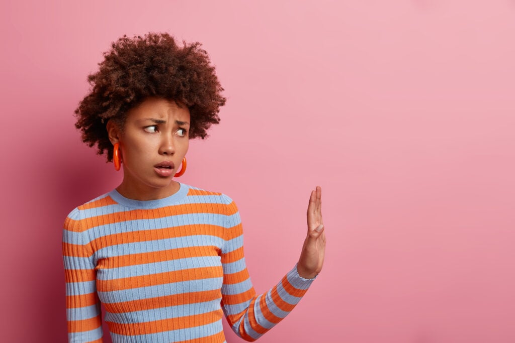 a young woman holding up her hand seemingly to avoid someone