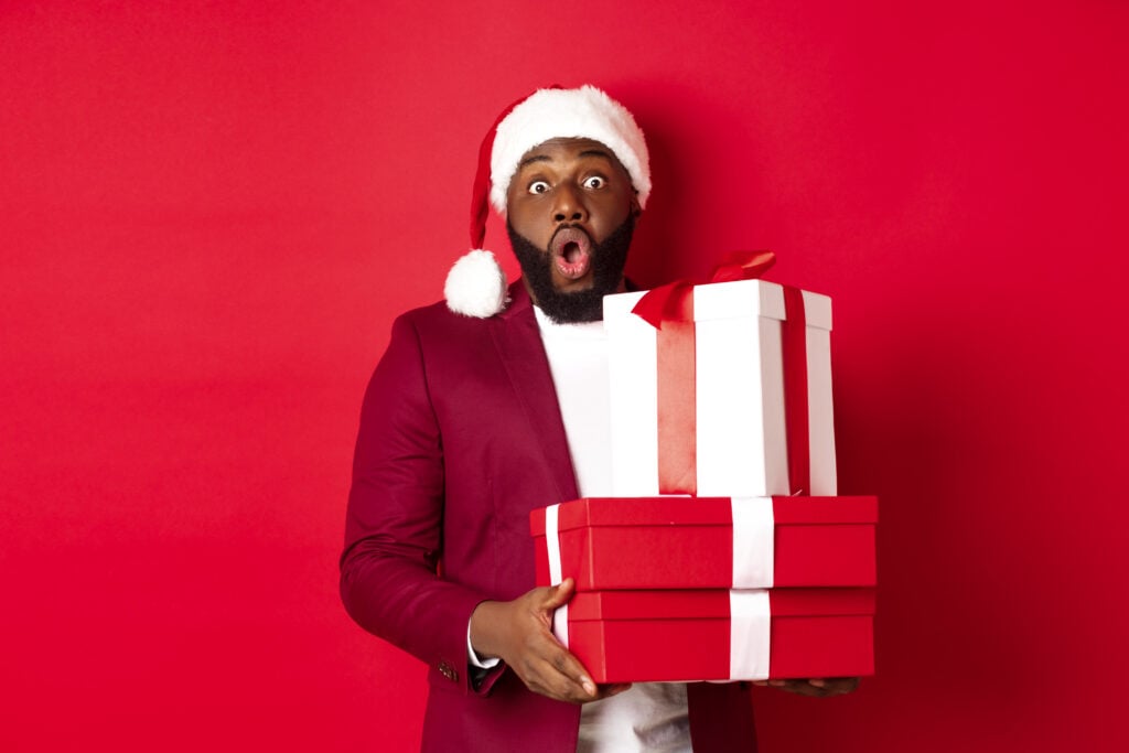 A young black man looking surprised at the gift he has in his hands