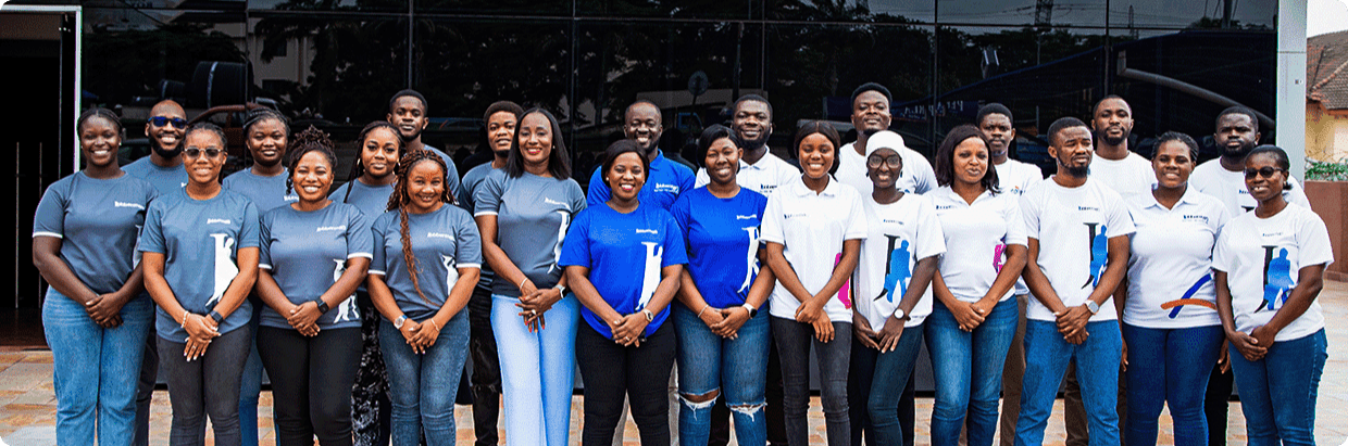 A group of smiling Jobberman Ghana employees standing together in two rows, wearing a mix of blue, gray, and white branded t-shirts, posing in front of a building. Above them, text reads: 'Learn About Your Prospects with Jobberman Ghana. Join the Jobberman Ghana Team Today!' with a button below that says 'Explore careers' in the center.